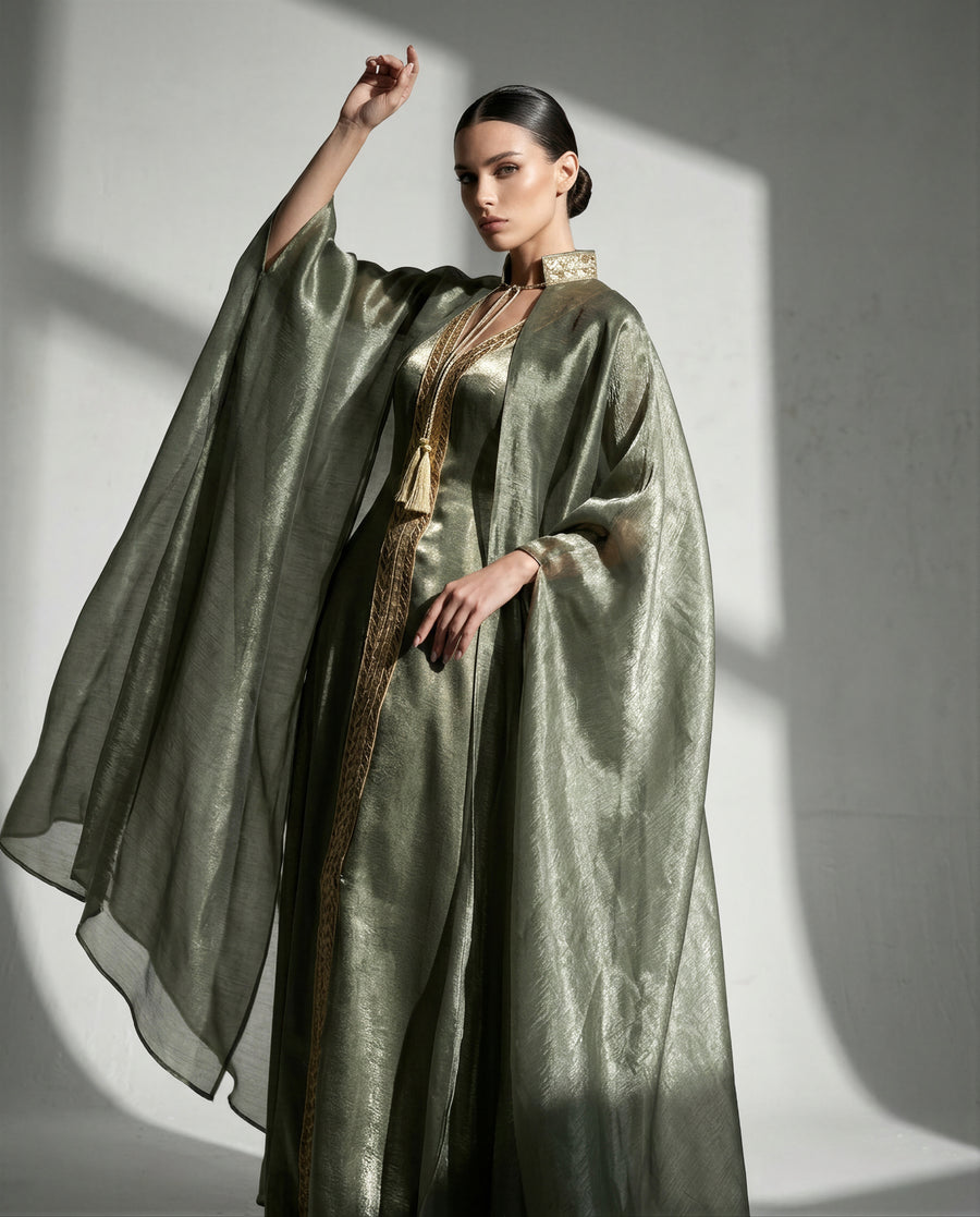 Sage silk kaftan with a gold-embroidered collar, arm raised