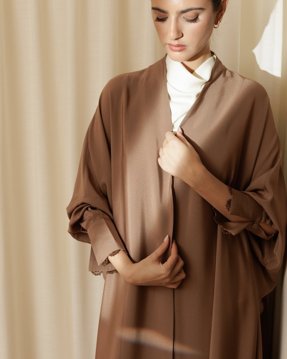 Model in the G224-M mocha crepe abaya with lace-trimmed cuffs over a cream high-neck top - MIRA Y MANO