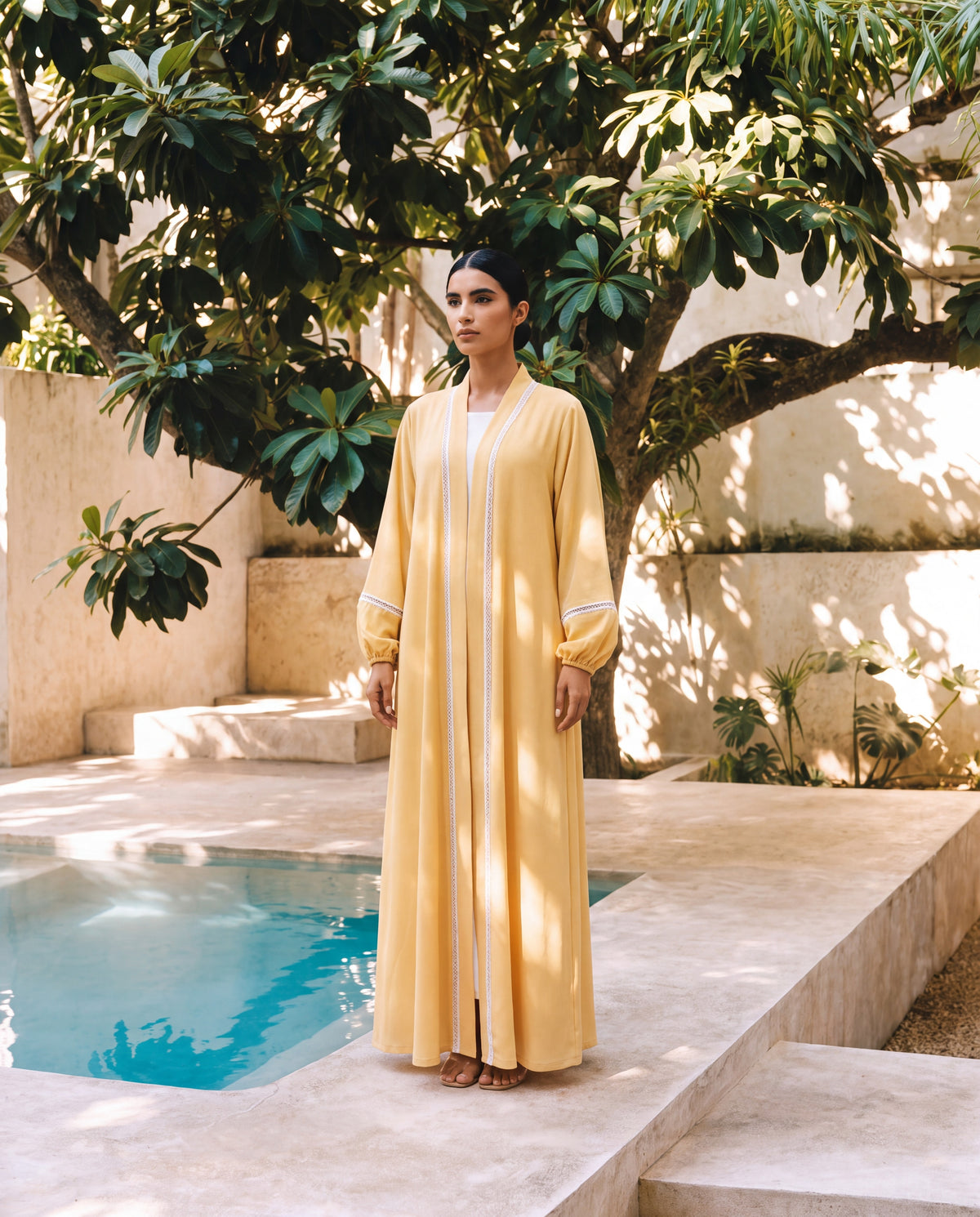 Model in the Effa yellow crepe abaya beside a garden pool