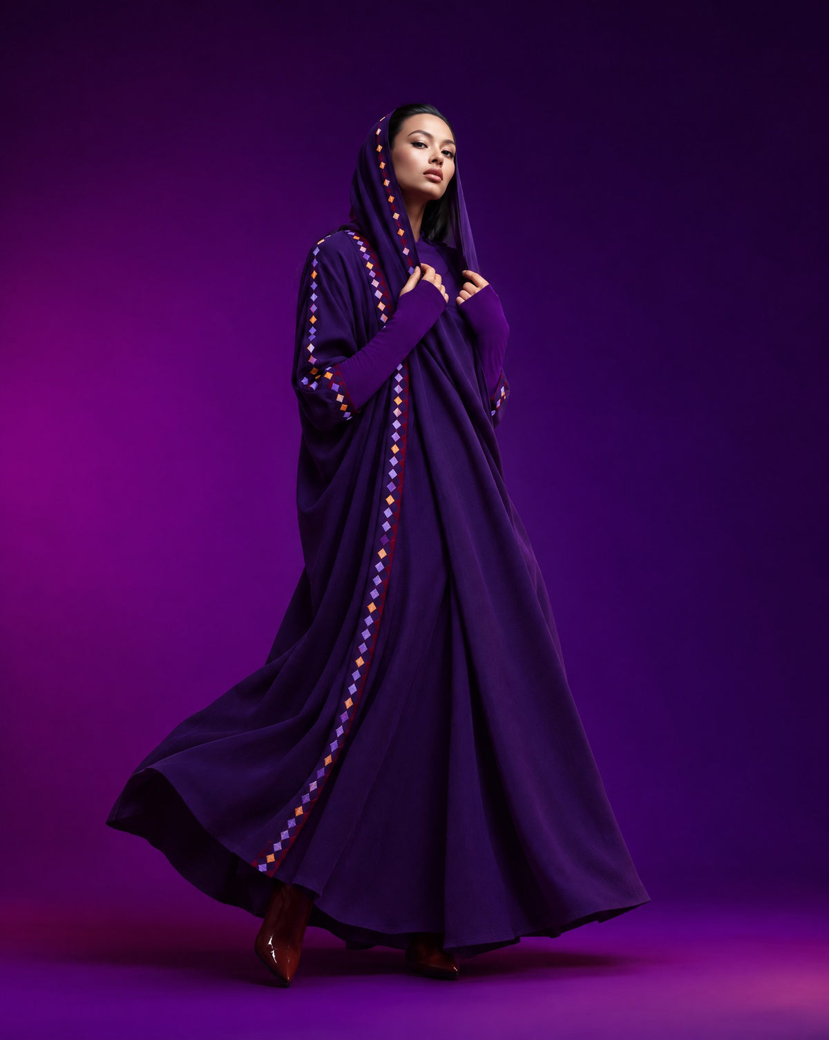 Model in a purple crepe abaya with a hood and a coloured diamond trim, against a violet backdrop