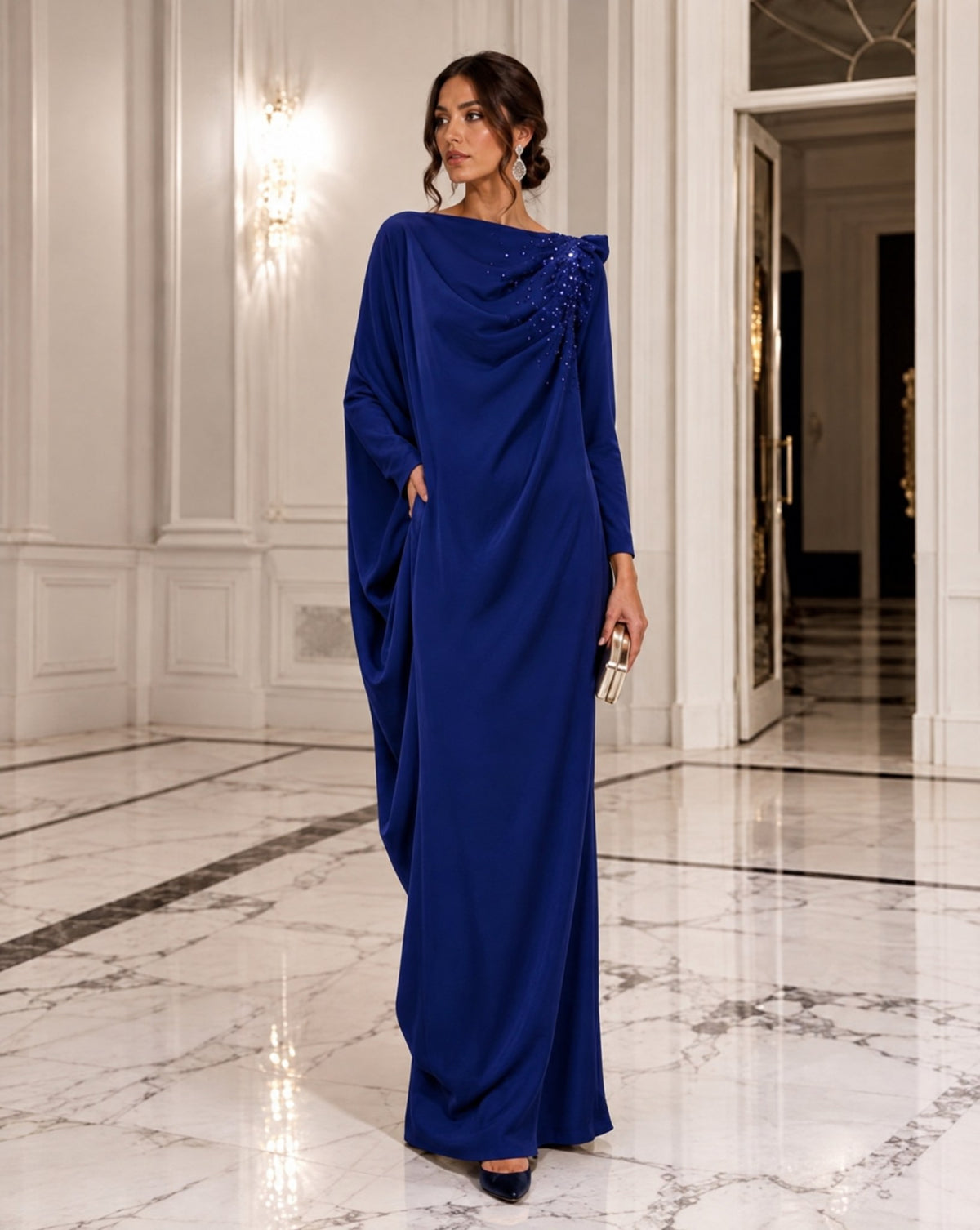 Model in a royal blue draped crepe dress in a marble hall