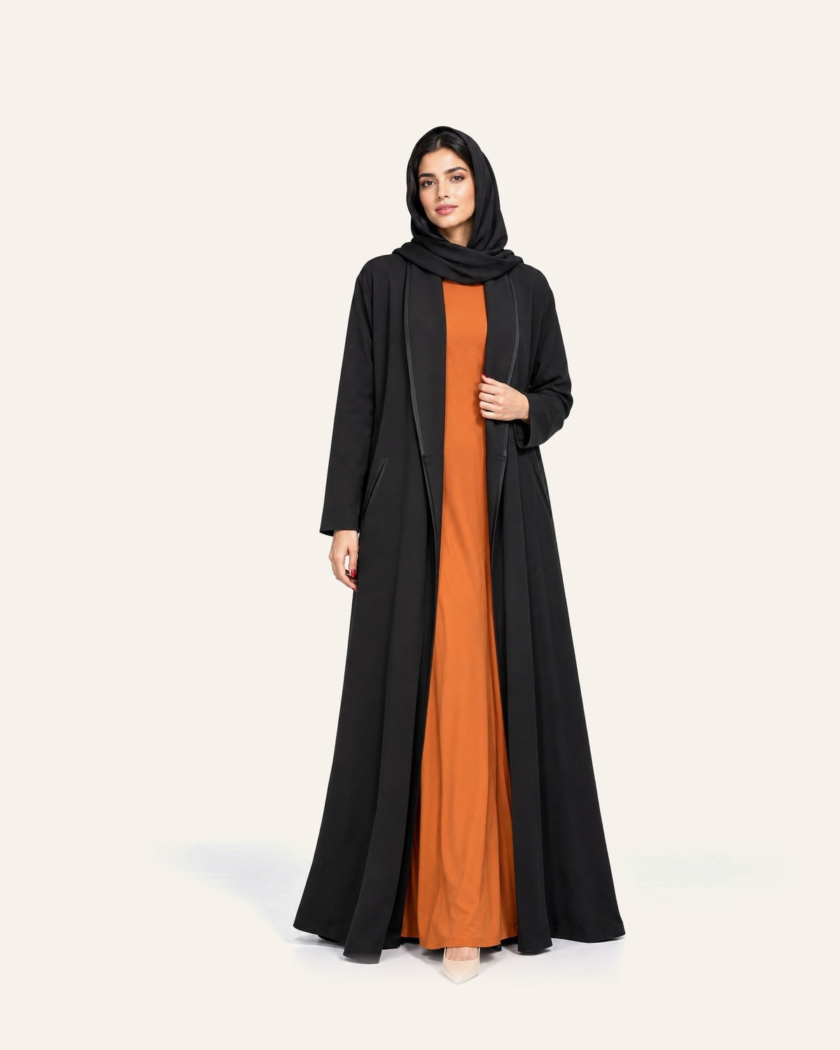 Amber Feroz AF Coat black crepe abaya over an amber dress, beside the SNM black jacquard abaya