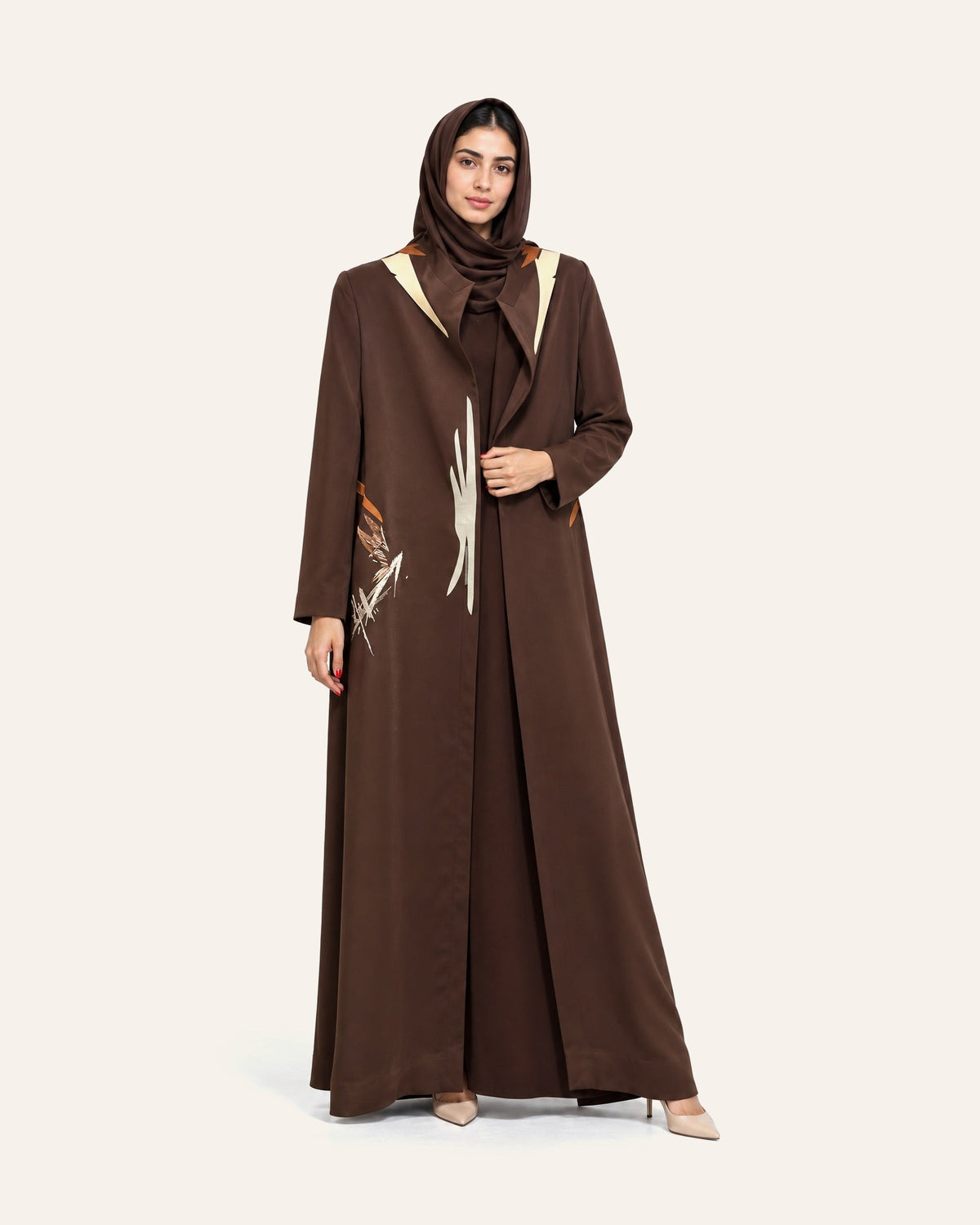 Amber Feroz SNM brown crepe abaya beside the SNM plum jacquard abaya, on a plain cream studio background