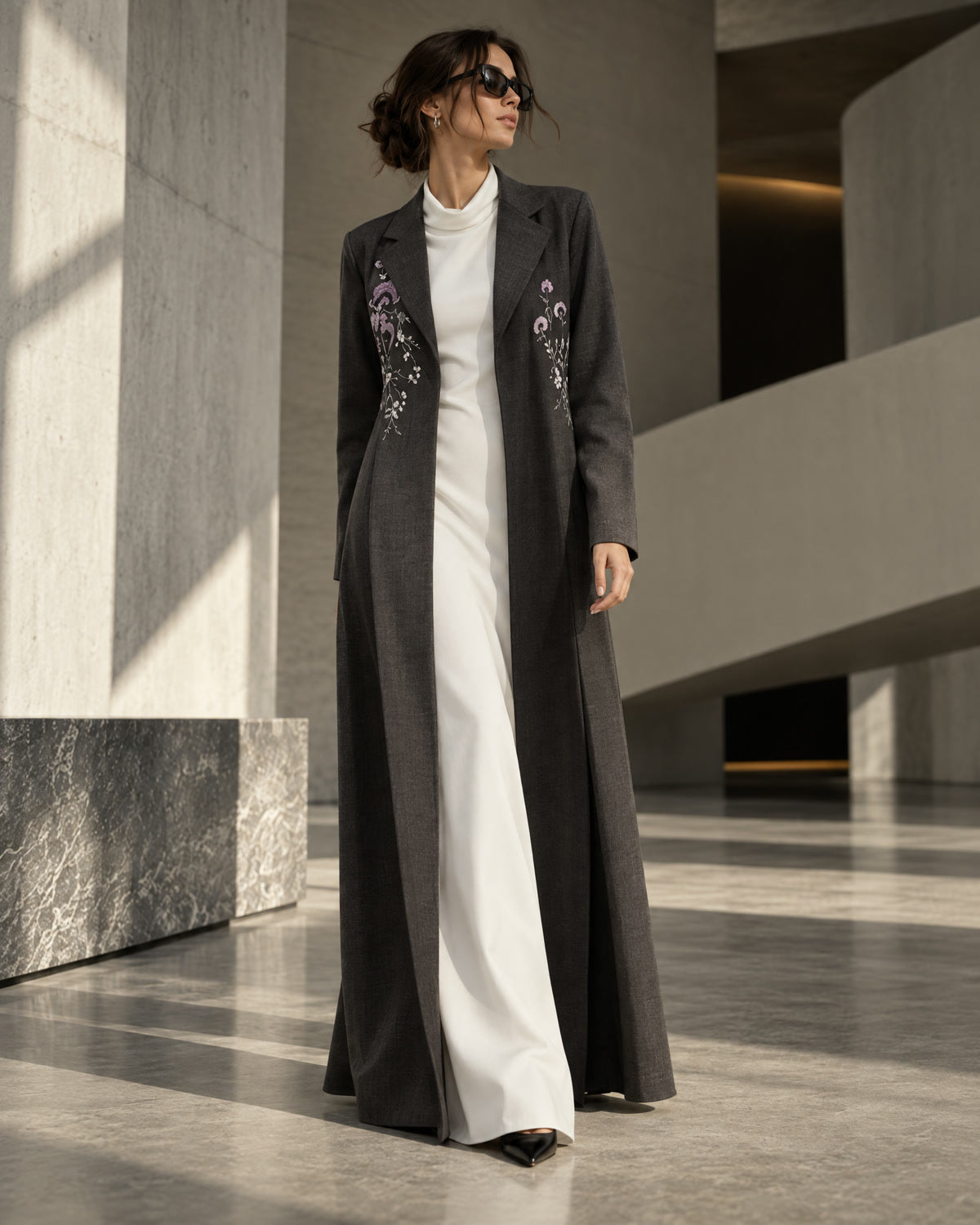 Model in a charcoal embroidered coat abaya over white trousers